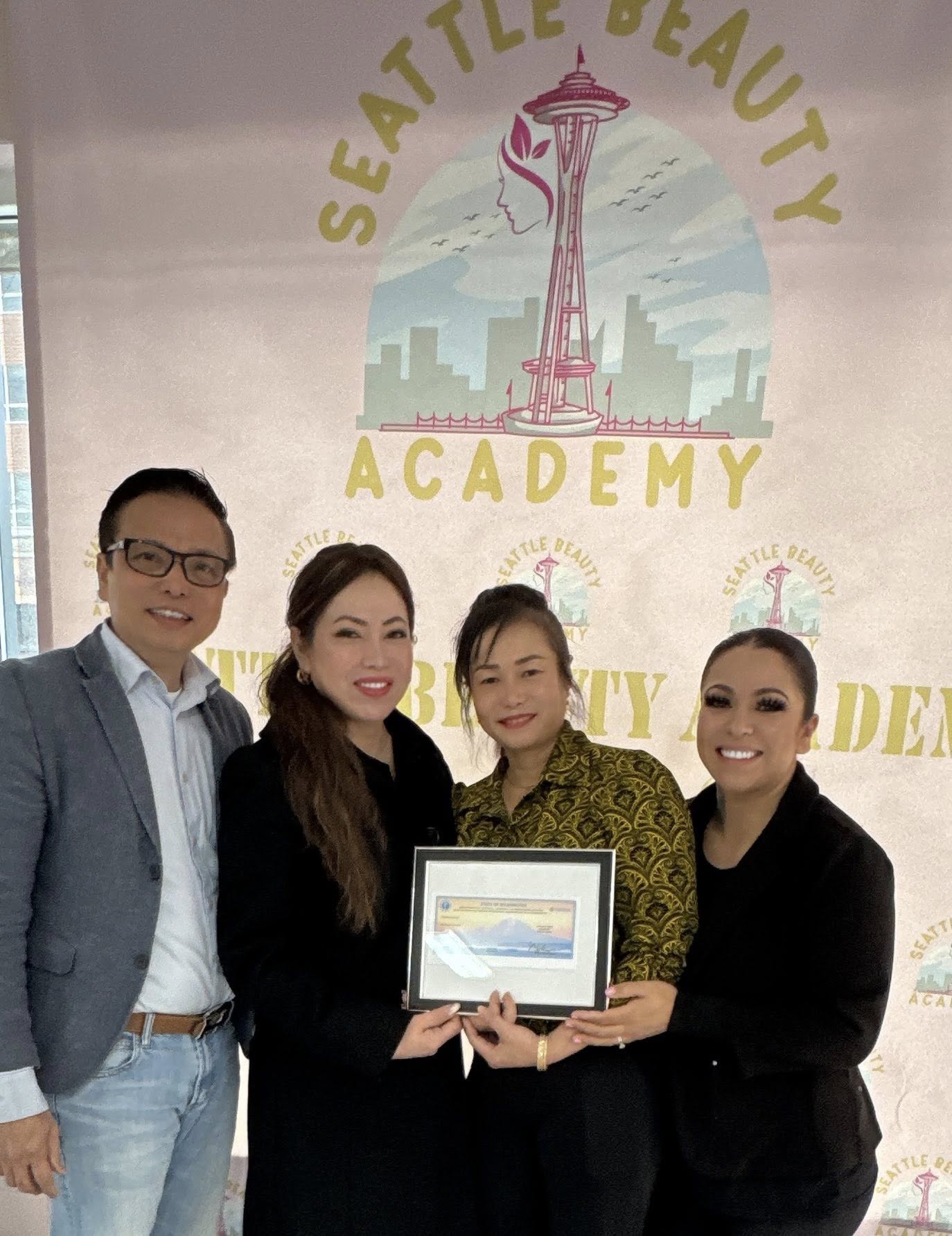 Seattle Beauty Academy team celebrating cosmetology certification with framed Washington State certificate Seattle Beauty Academy team celebrating cosmetology certification with framed Washington State certificate