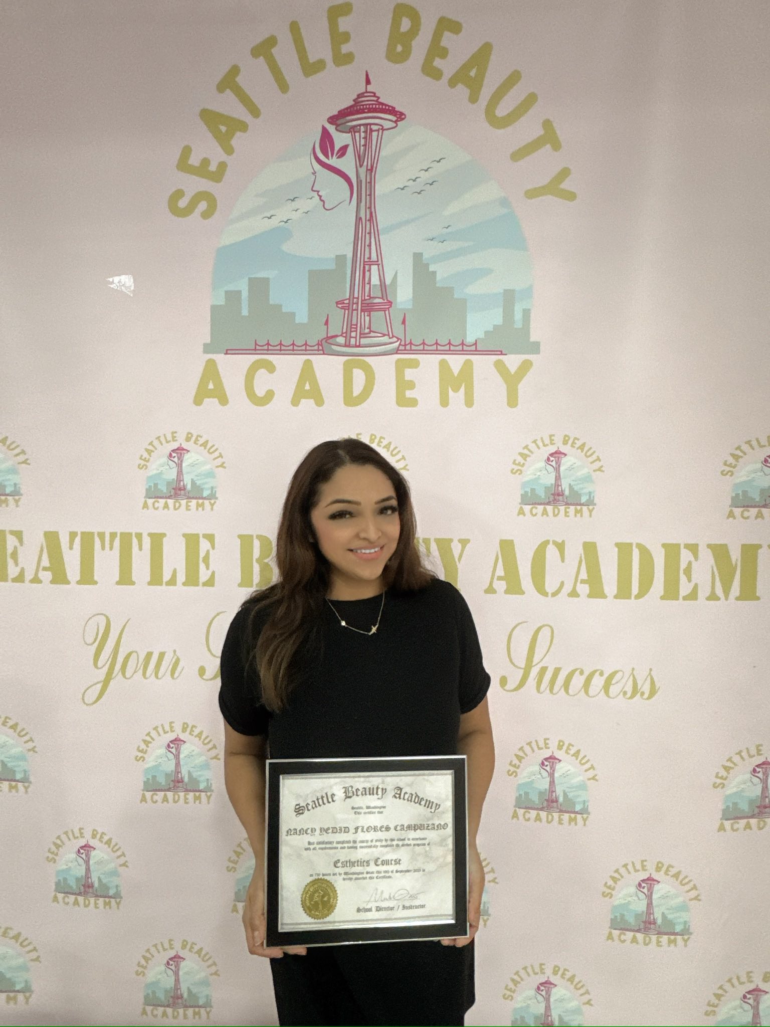 A graduate of the esthetics program proudly holds her completion certificate at Seattle Beauty Academy. A graduate of the esthetics program proudly holds her completion certificate at Seattle Beauty Academy.
