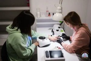 Modern nail salon setup with LED UV lamp, gel polish collection, and chrome nail art tools on technician workstation
