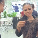 Bilingual hair design instructor reviewing translated lesson materials with a Spanish-speaking student in a Seattle beauty school classroom