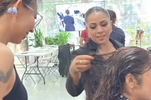 Bilingual hair design instructor reviewing translated lesson materials with a Spanish-speaking student in a Seattle beauty school classroom