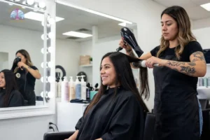 Licensed Hispanic hair designer blow-drying a smiling client's long dark hair at a modern Seattle salon