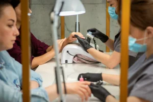 Nail technician wearing protective gloves and mask during chemical nail service following Washington State safety standards