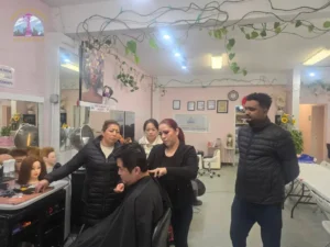 Barbering instructor at Seattle Beauty Academy teaching students haircut technique on a live client in Seattle, Washington