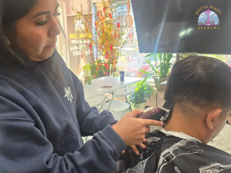 Seattle Beauty Academy barbering student practicing clipper technique on a live client during hands-on training