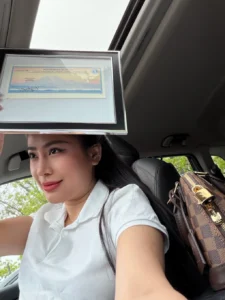 A Seattle Beauty Academy graduate holds up her framed Washington State license in the car right after graduation — a quiet, joyful moment of finally holding the proof of everything she worked for.