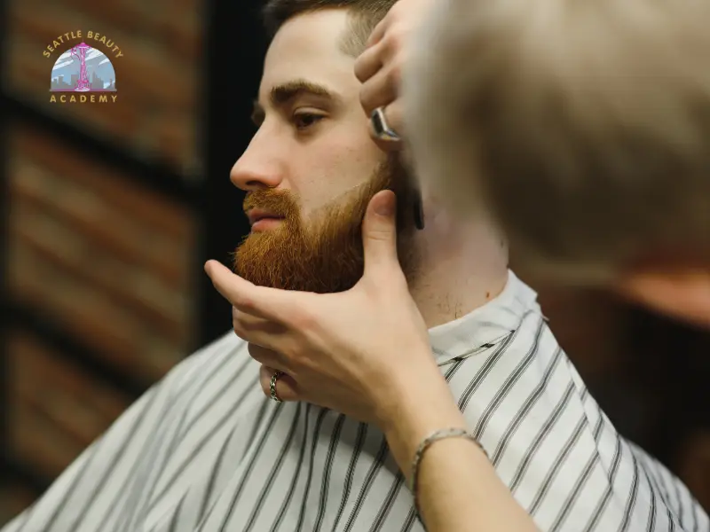 Barber student shaping a client's beard during hands-on beard grooming techniques training at Seattle Beauty Academy