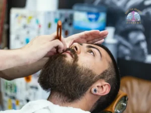 Professional beard detailing and mustache shaping with a straight razor during barber training at Seattle Beauty Academy